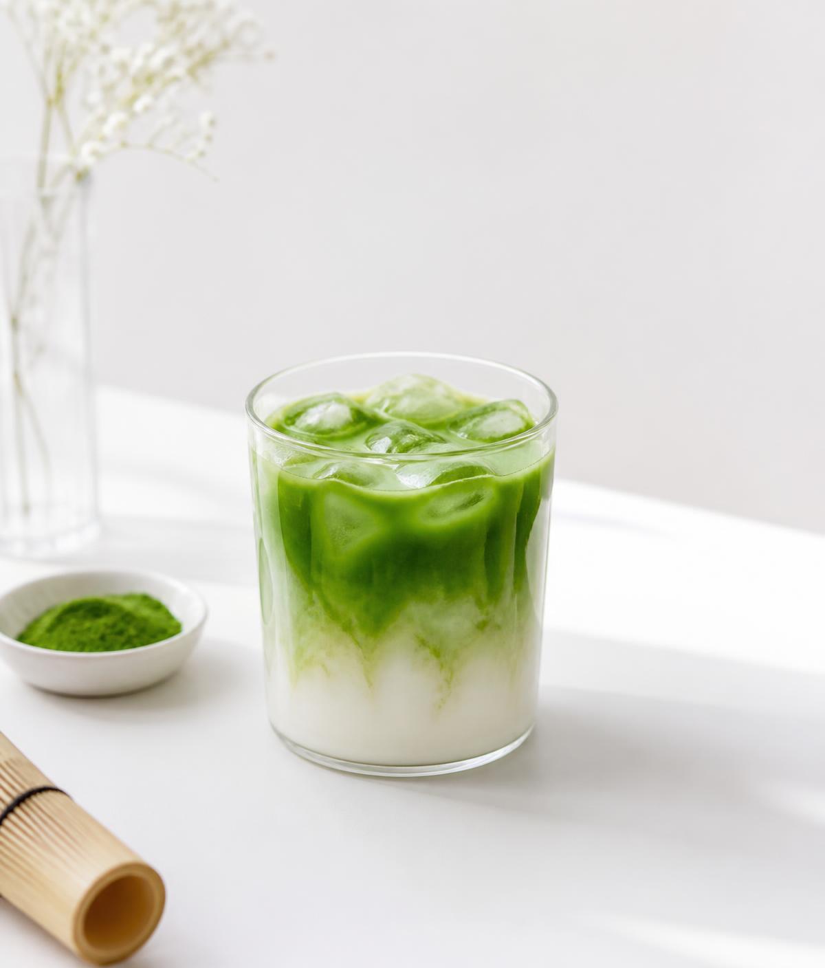 Iced matcha latte in a clear glass on a bright white surface